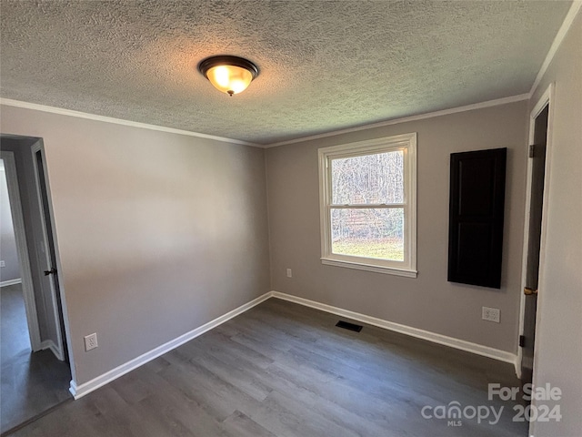 empty room with a textured ceiling, dark hardwood / wood-style flooring, and ornamental molding