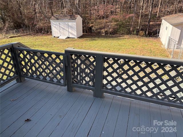 wooden terrace featuring a yard and a storage unit