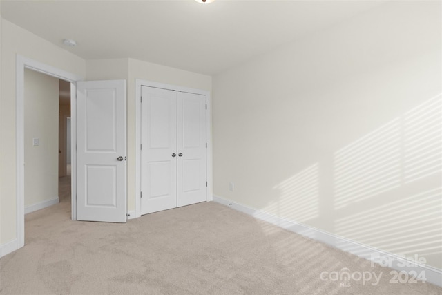 unfurnished bedroom featuring a closet and light colored carpet