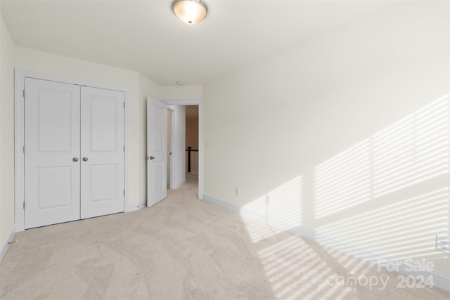 unfurnished bedroom featuring light colored carpet and a closet