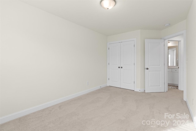 unfurnished bedroom with light carpet and a closet