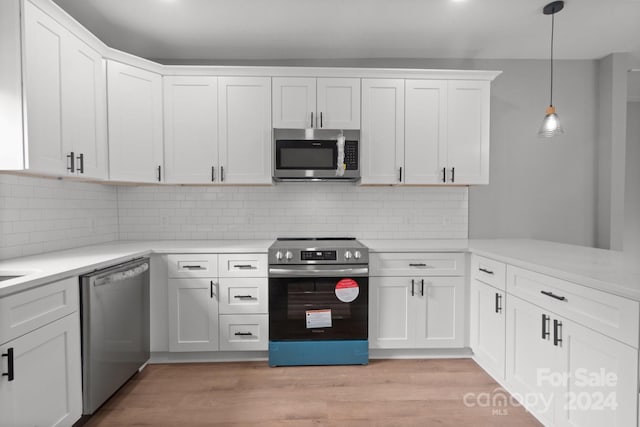 kitchen featuring decorative backsplash, appliances with stainless steel finishes, light hardwood / wood-style flooring, white cabinets, and hanging light fixtures