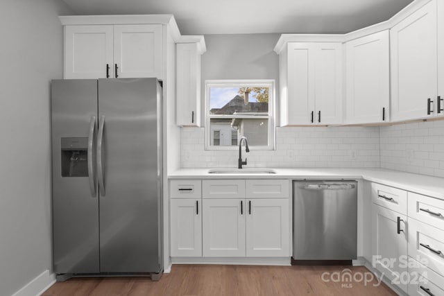 kitchen with white cabinetry, sink, appliances with stainless steel finishes, and light hardwood / wood-style flooring