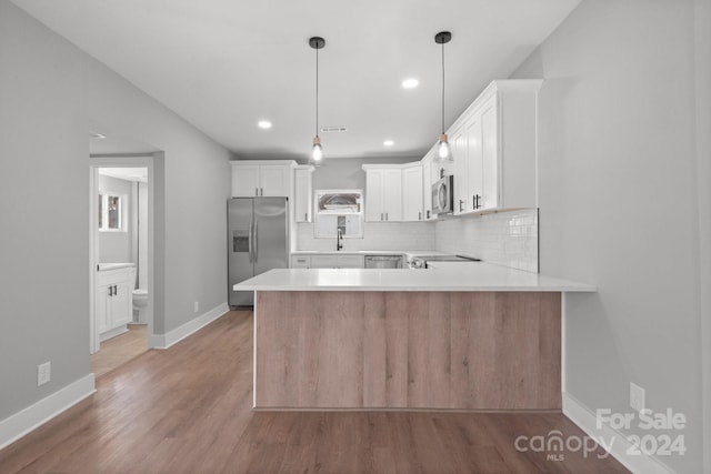 kitchen featuring light hardwood / wood-style flooring, decorative light fixtures, white cabinetry, kitchen peninsula, and stainless steel appliances