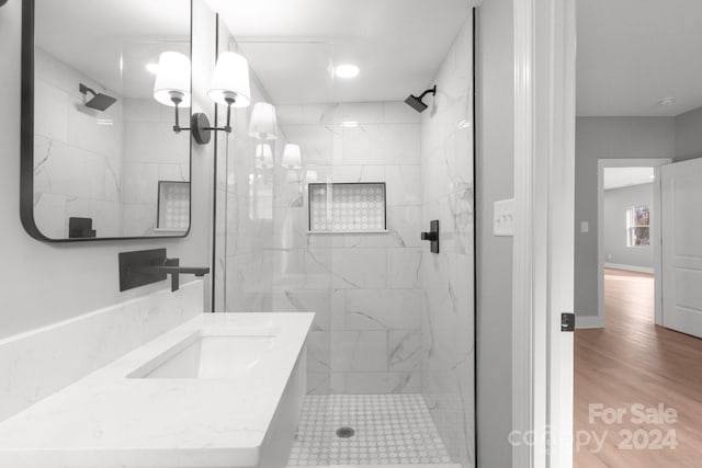 bathroom with hardwood / wood-style flooring, vanity, a tile shower, and an inviting chandelier