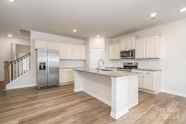 kitchen featuring a center island with sink, light hardwood / wood-style floors, and appliances with stainless steel finishes