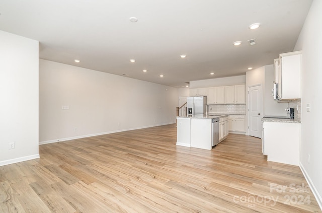 kitchen featuring a center island with sink, white cabinetry, light wood-type flooring, and stainless steel appliances