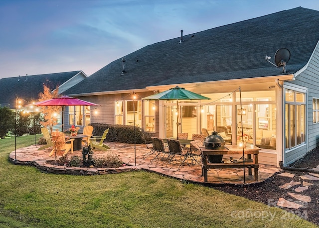 back house at dusk featuring a patio area, a yard, and an outdoor fire pit