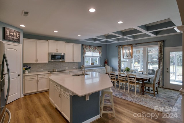 kitchen with pendant lighting, a healthy amount of sunlight, light wood-type flooring, and stainless steel appliances