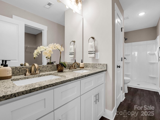 bathroom featuring vanity, hardwood / wood-style floors, a shower, and toilet