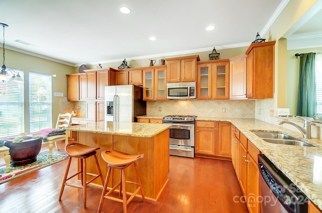 kitchen with stainless steel appliances, sink, wood-type flooring, pendant lighting, and a center island