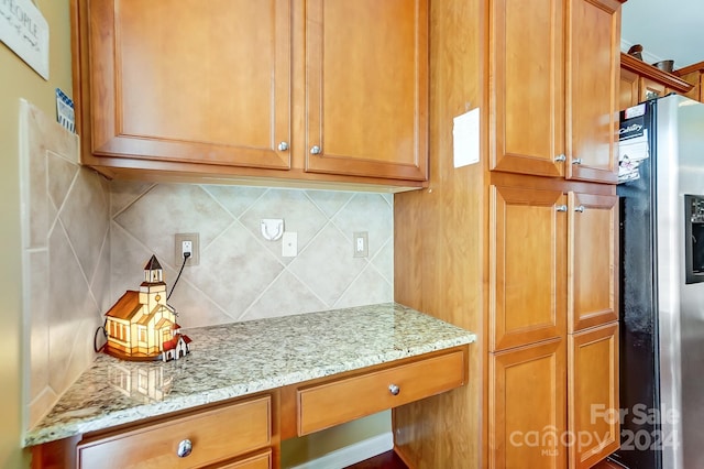 kitchen featuring decorative backsplash, light stone countertops, and stainless steel fridge with ice dispenser