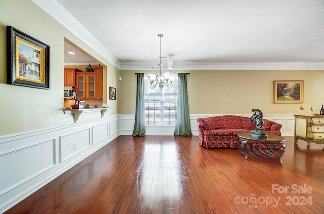 living area with ornamental molding, dark wood-type flooring, and an inviting chandelier