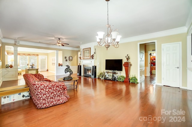 living room featuring wood-type flooring, ceiling fan with notable chandelier, and crown molding