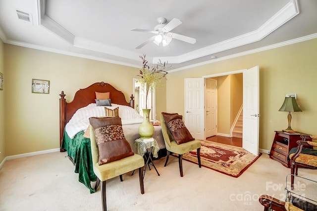 carpeted bedroom featuring a tray ceiling, ceiling fan, and ornamental molding