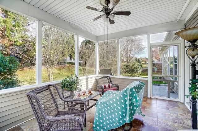 unfurnished sunroom with ceiling fan, a healthy amount of sunlight, and wood ceiling