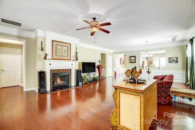 living area with visible vents, a fireplace with flush hearth, wood finished floors, and crown molding