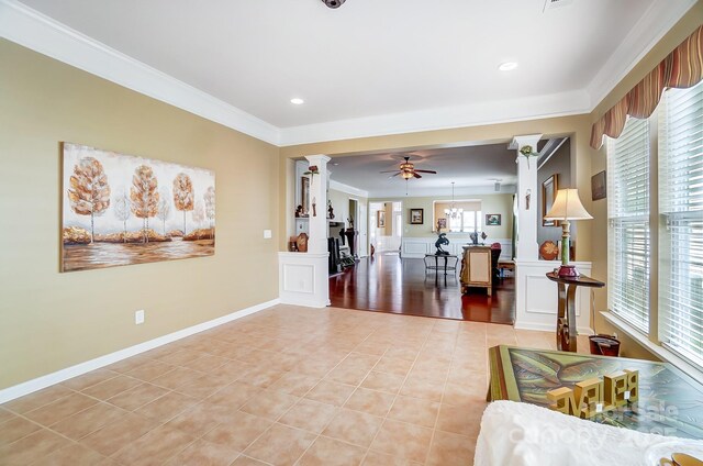 living area with light tile patterned floors, baseboards, ornate columns, ceiling fan, and ornamental molding