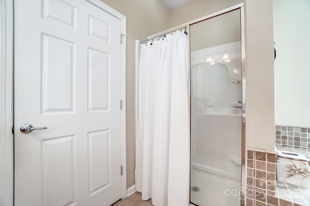 full bath featuring a shower with shower curtain, decorative backsplash, and tile patterned flooring