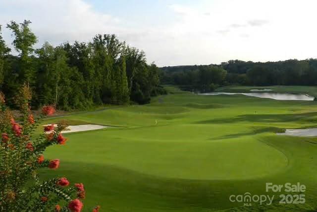 view of property's community with a water view, a lawn, and golf course view