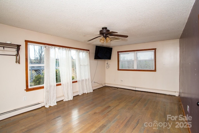 empty room with dark hardwood / wood-style floors, ceiling fan, a healthy amount of sunlight, and a textured ceiling