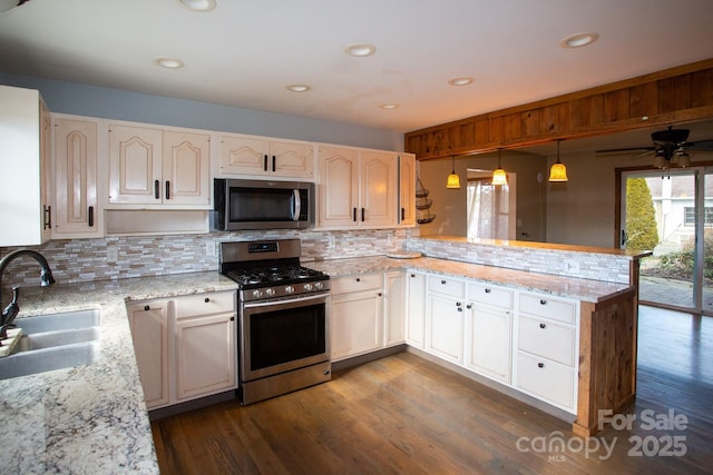 kitchen featuring backsplash, hanging light fixtures, sink, appliances with stainless steel finishes, and kitchen peninsula