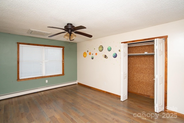 unfurnished bedroom with a closet, a baseboard radiator, ceiling fan, and dark wood-type flooring