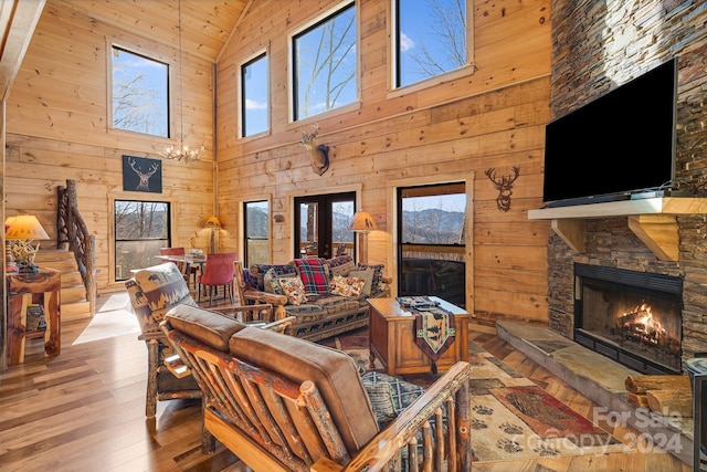 living room featuring wood walls, a stone fireplace, light wood-type flooring, and high vaulted ceiling