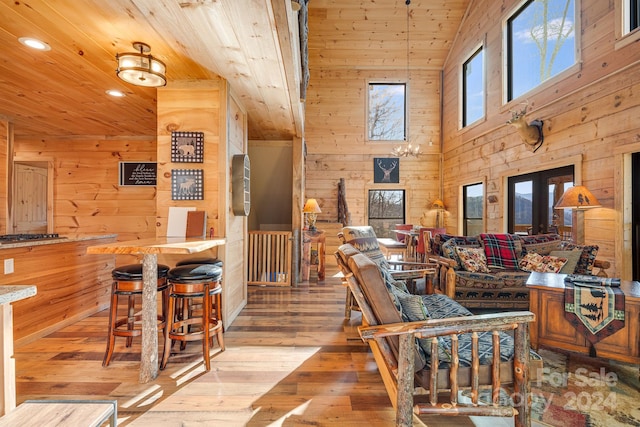 living room with french doors, wood ceiling, wooden walls, high vaulted ceiling, and light hardwood / wood-style flooring