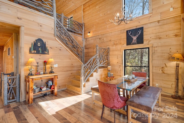 dining area with wood-type flooring, an inviting chandelier, and wooden walls