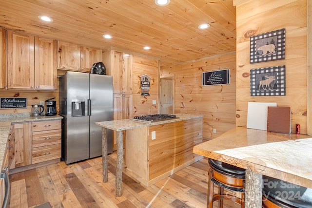 kitchen featuring light stone counters, light brown cabinetry, light wood-type flooring, and appliances with stainless steel finishes