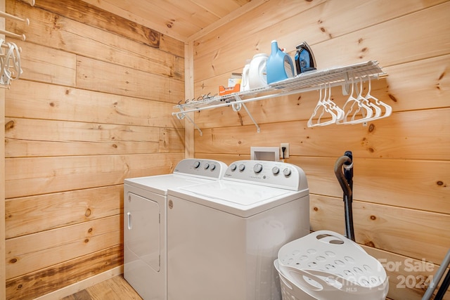 laundry area featuring wooden walls, light hardwood / wood-style floors, and independent washer and dryer