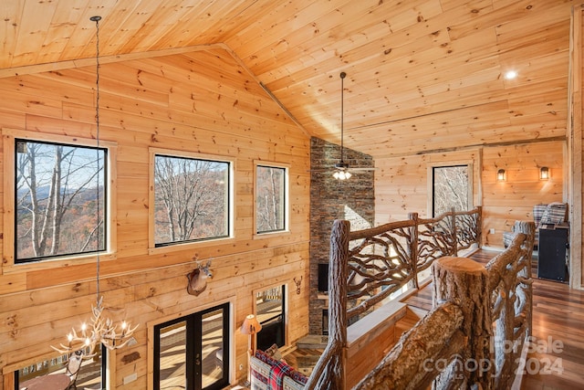 interior space with wood ceiling, ceiling fan with notable chandelier, high vaulted ceiling, hardwood / wood-style floors, and wood walls