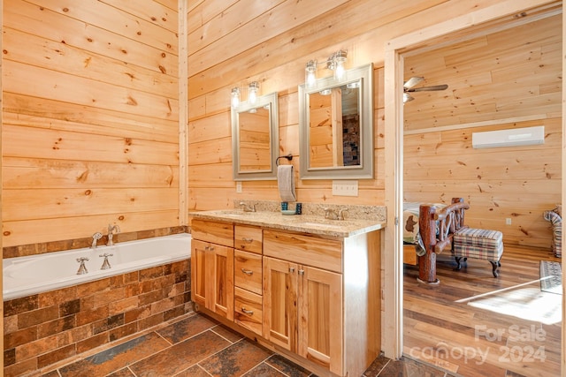 bathroom with a bathing tub, wooden walls, vanity, and hardwood / wood-style flooring