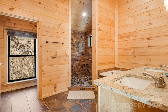 bathroom with tiled shower, vanity, vaulted ceiling, and wood walls