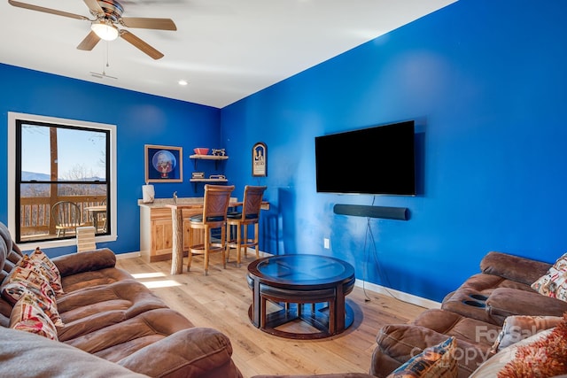 living room featuring bar, light hardwood / wood-style flooring, and ceiling fan