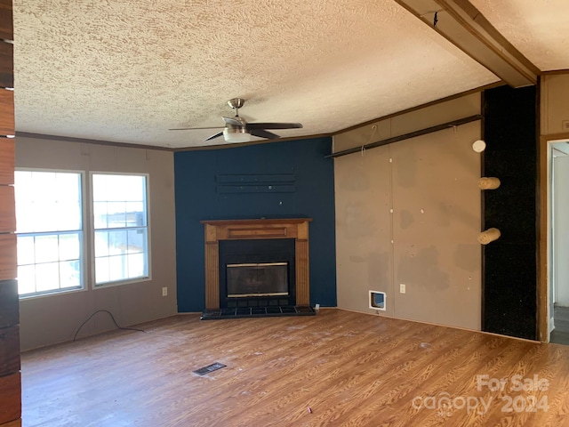 unfurnished living room featuring hardwood / wood-style floors, ceiling fan, ornamental molding, a textured ceiling, and beamed ceiling