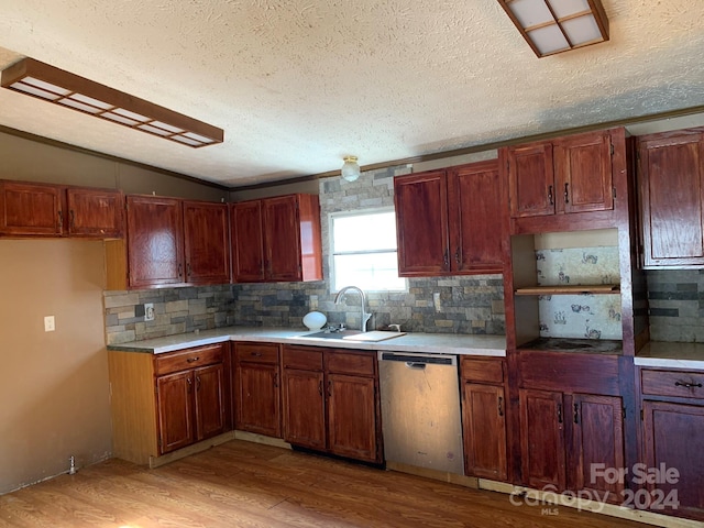 kitchen with a textured ceiling, light wood-type flooring, stainless steel dishwasher, and sink