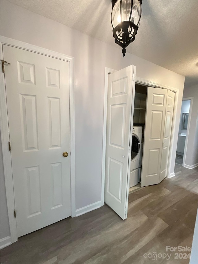 unfurnished bedroom with hardwood / wood-style flooring, washer / dryer, a textured ceiling, and a closet