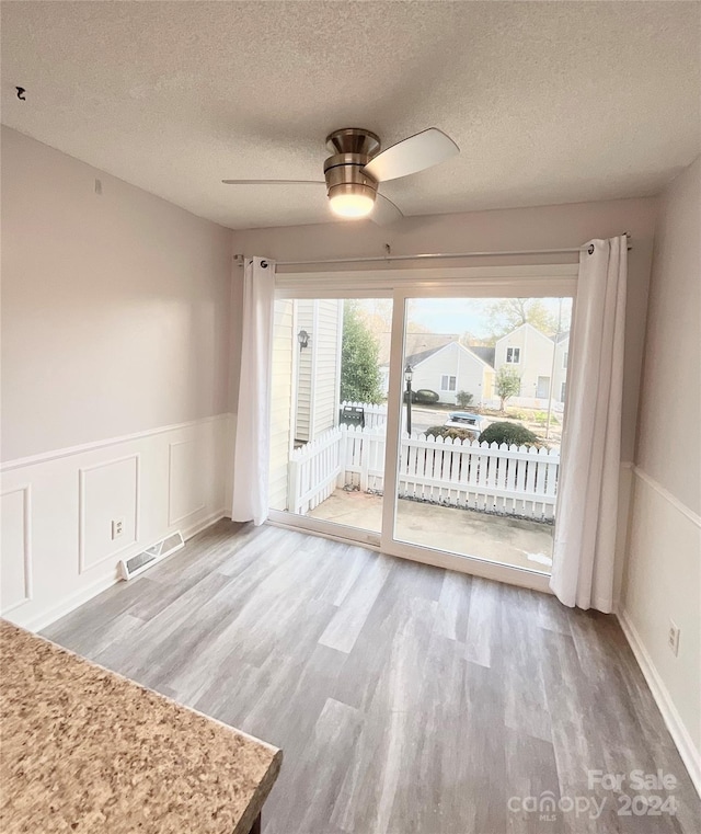 interior space with a wealth of natural light, ceiling fan, a textured ceiling, and hardwood / wood-style flooring