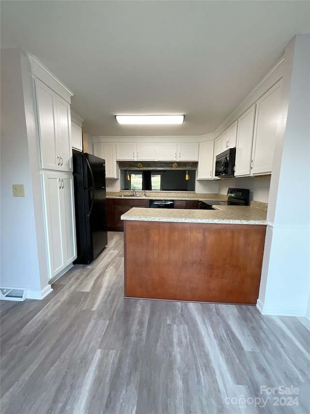 kitchen with white cabinets, light wood-type flooring, kitchen peninsula, and black appliances