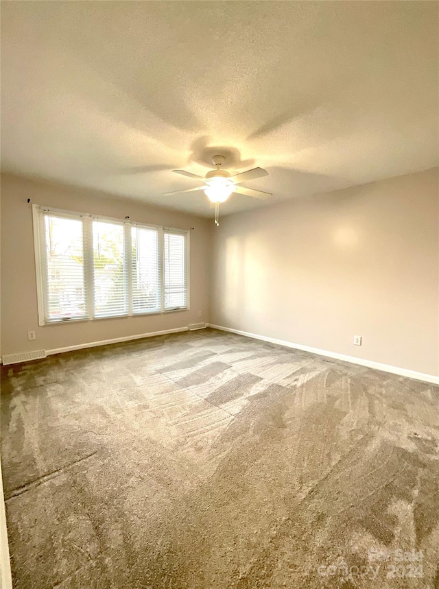 carpeted empty room featuring ceiling fan and a textured ceiling