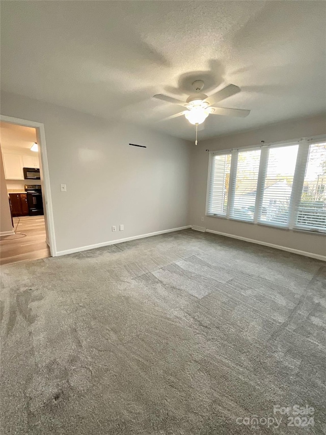 empty room with light carpet, a textured ceiling, and ceiling fan