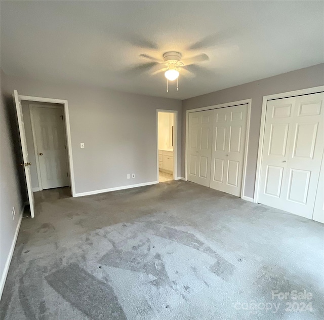 unfurnished bedroom featuring carpet flooring, two closets, and ceiling fan