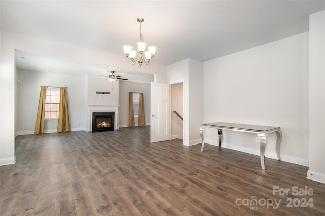 unfurnished living room with ceiling fan with notable chandelier and dark wood-type flooring