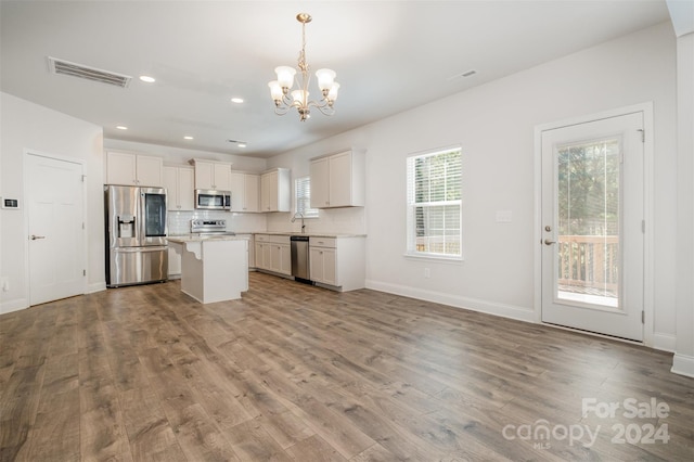 kitchen featuring an inviting chandelier, white cabinets, hanging light fixtures, a kitchen island, and stainless steel appliances