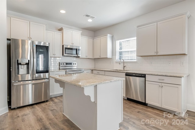 kitchen featuring a center island, white cabinets, sink, appliances with stainless steel finishes, and light hardwood / wood-style floors