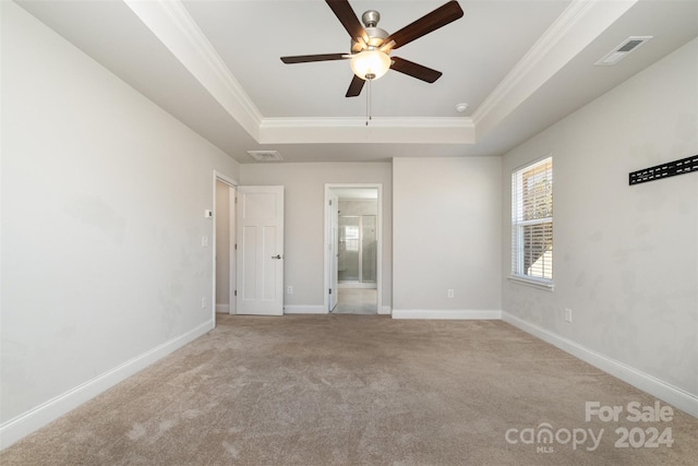 unfurnished room featuring light carpet, a tray ceiling, and crown molding