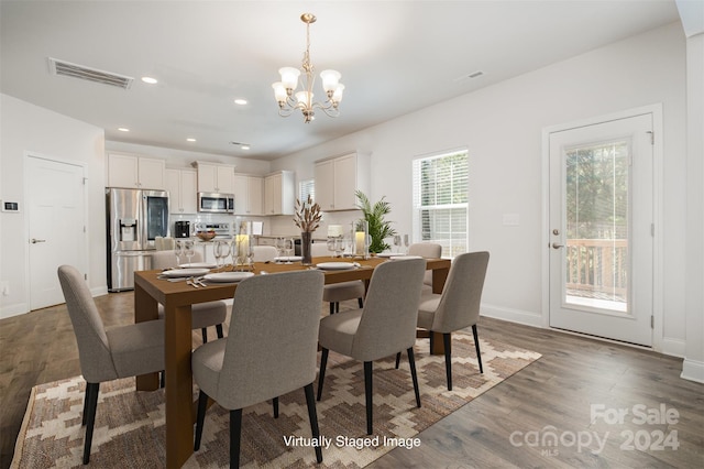 dining room with dark hardwood / wood-style floors and an inviting chandelier