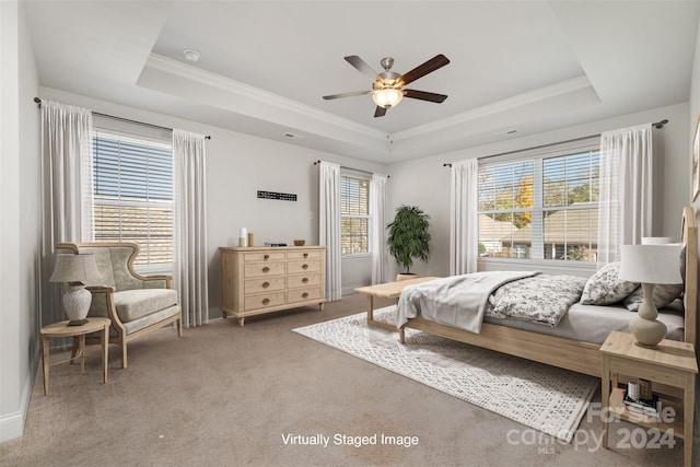 carpeted bedroom with ceiling fan, a raised ceiling, and crown molding